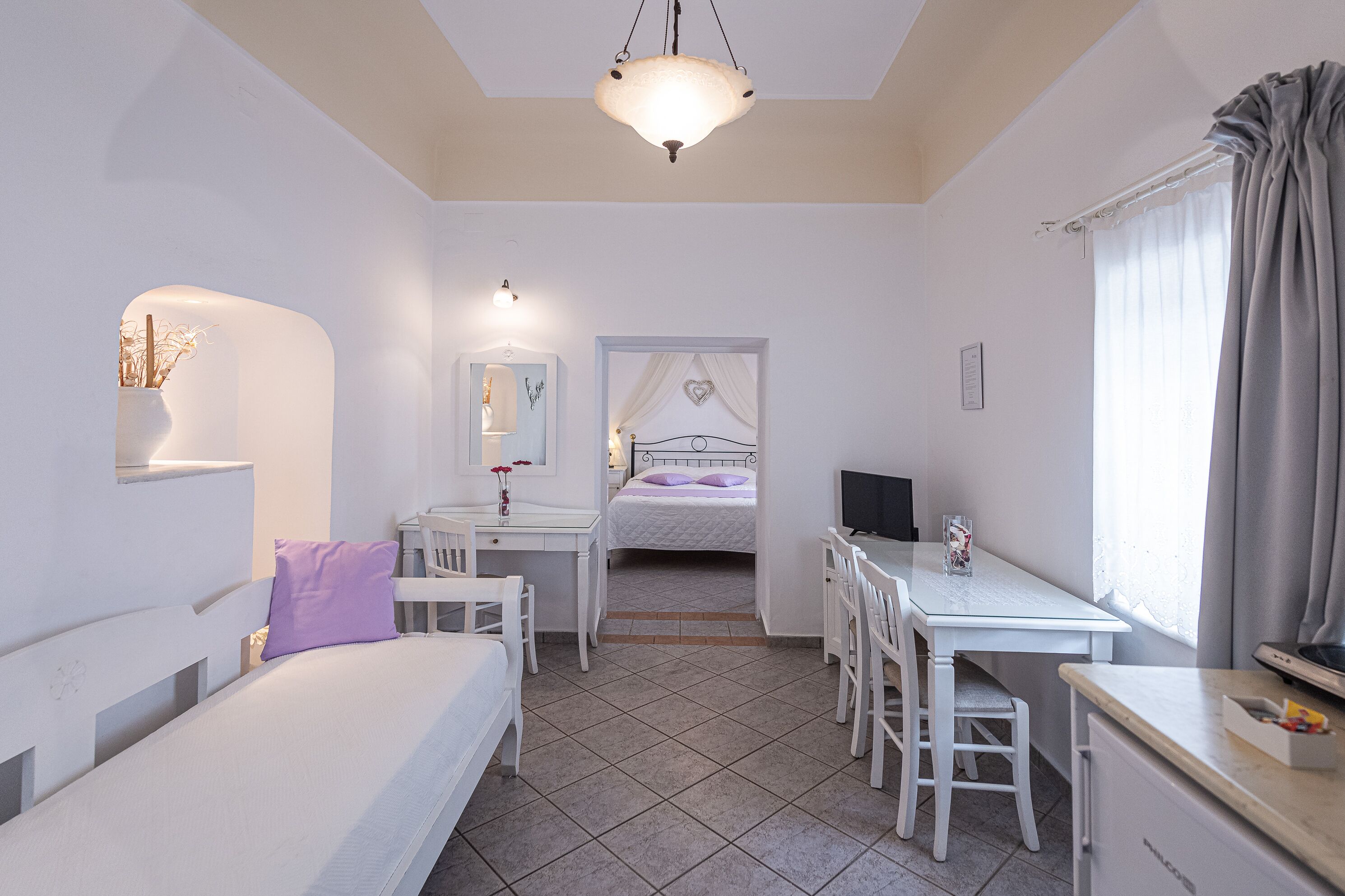 A bedroom with a bed, desk, and chair, a bathroom with a mirror and vanity, and a dining area with a table and chairs.