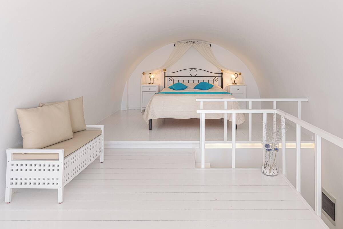 Ein Schlafzimmer mit einem Bett, einem Nachttisch, einer Bank und einer Zimmerpflanze.