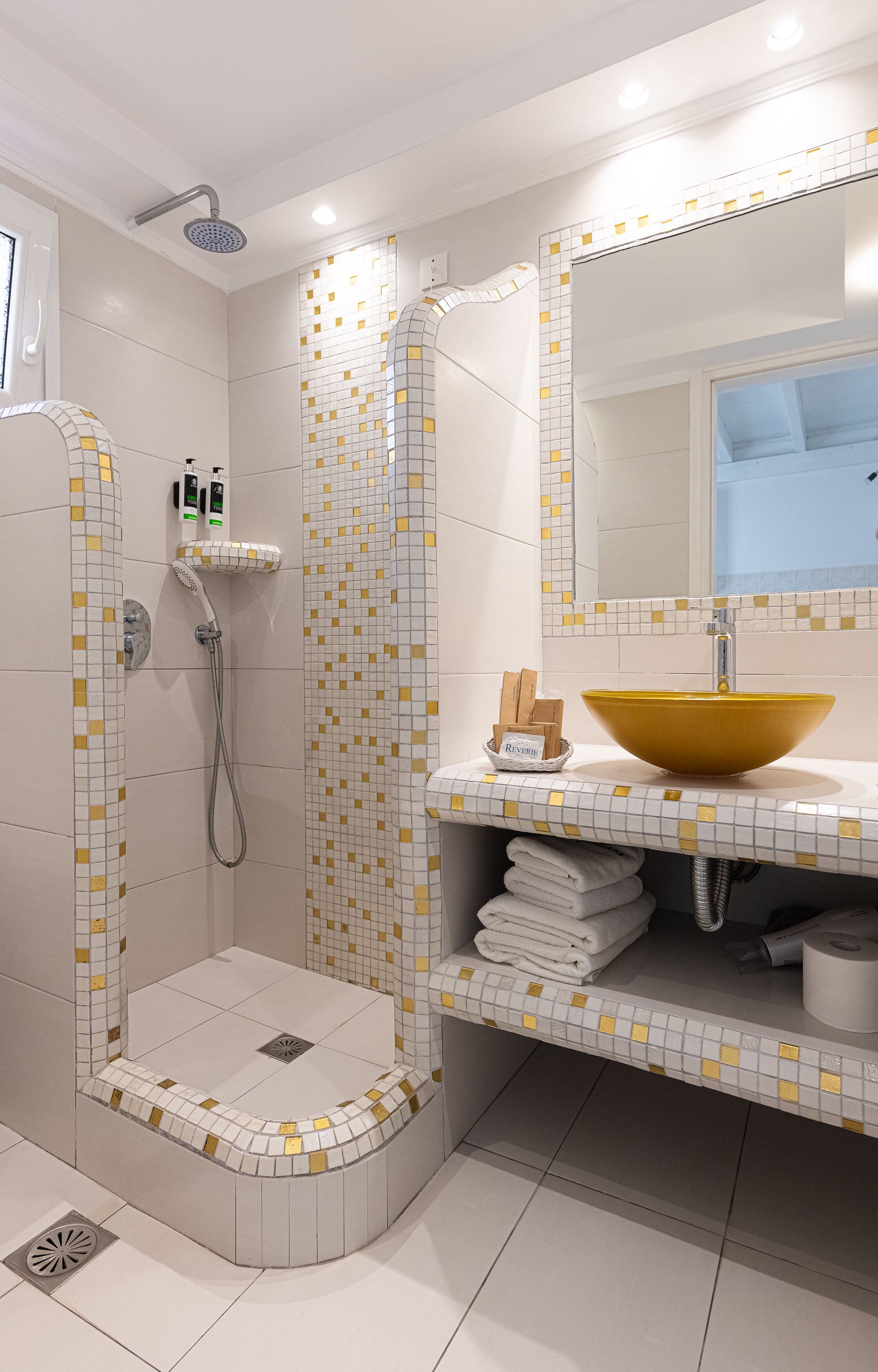 A bathroom with a shower, a sink with a yellow basin, and a mirror above the sink.