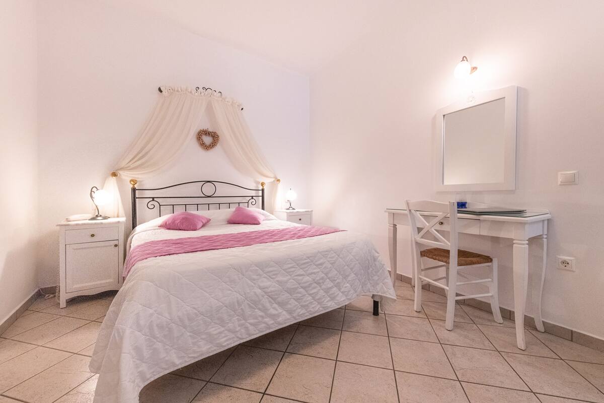 Ein Schlafzimmer mit einem Bett, Nachttischen, einem Schreibtisch und einem Sessel.