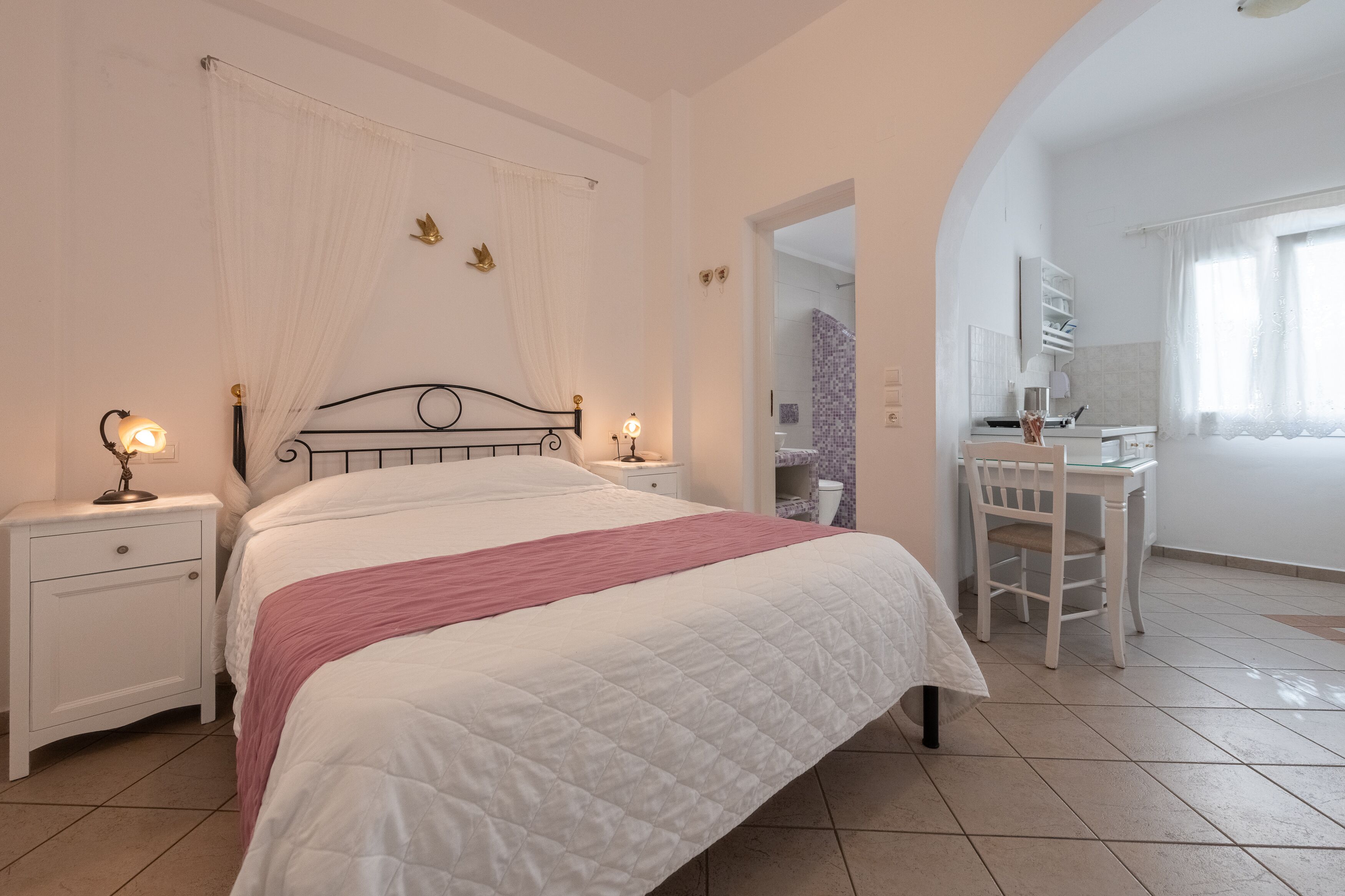 A bedroom with a bed, nightstands, a desk, and a chair.