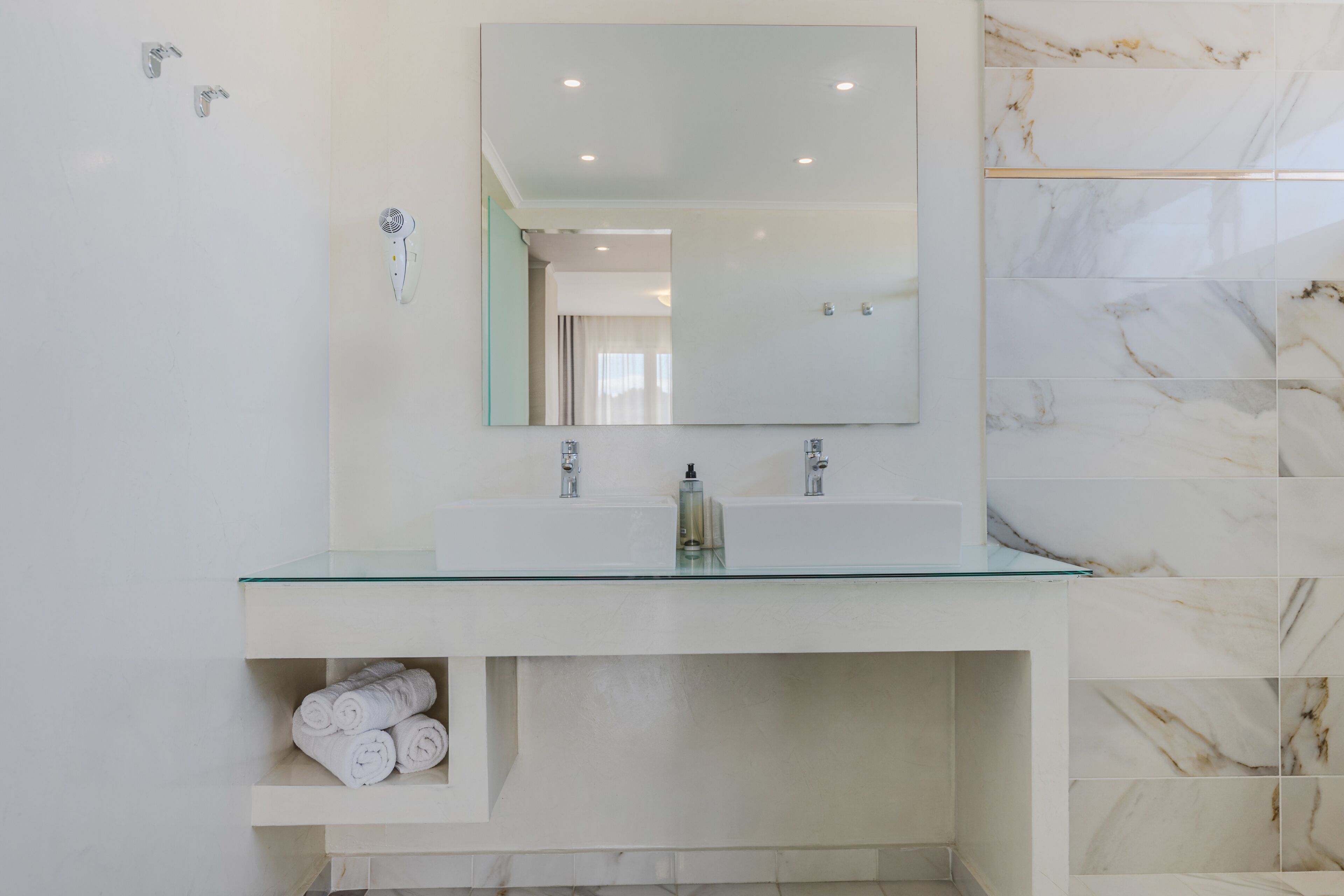 Un bagno moderno con un lavabo in vetro, uno specchio grande e piastrelle in marmo.