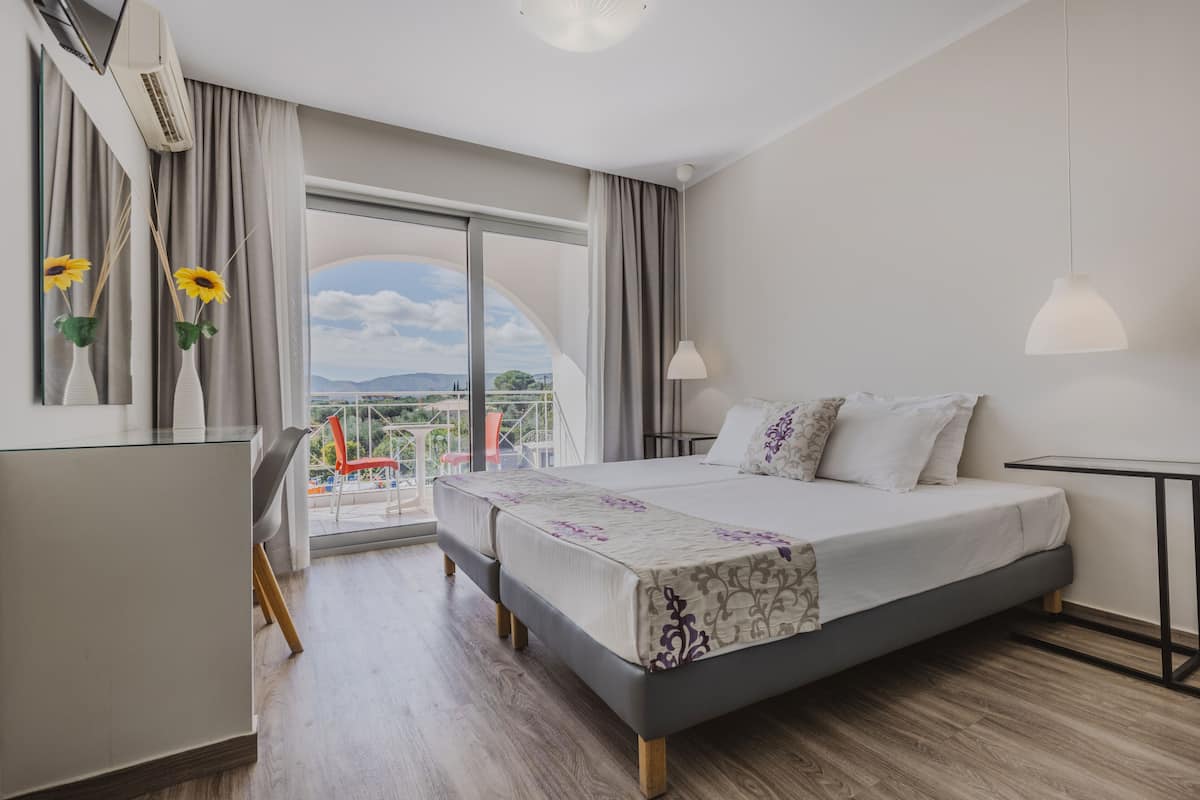 Une chambre d’hôtel moderne dotée d’un grand lit, d’un bureau et d’un balcon offrant une vue sur la ville.
