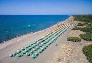 En la playa, playa de arena negra, camastros y sombrillas 
