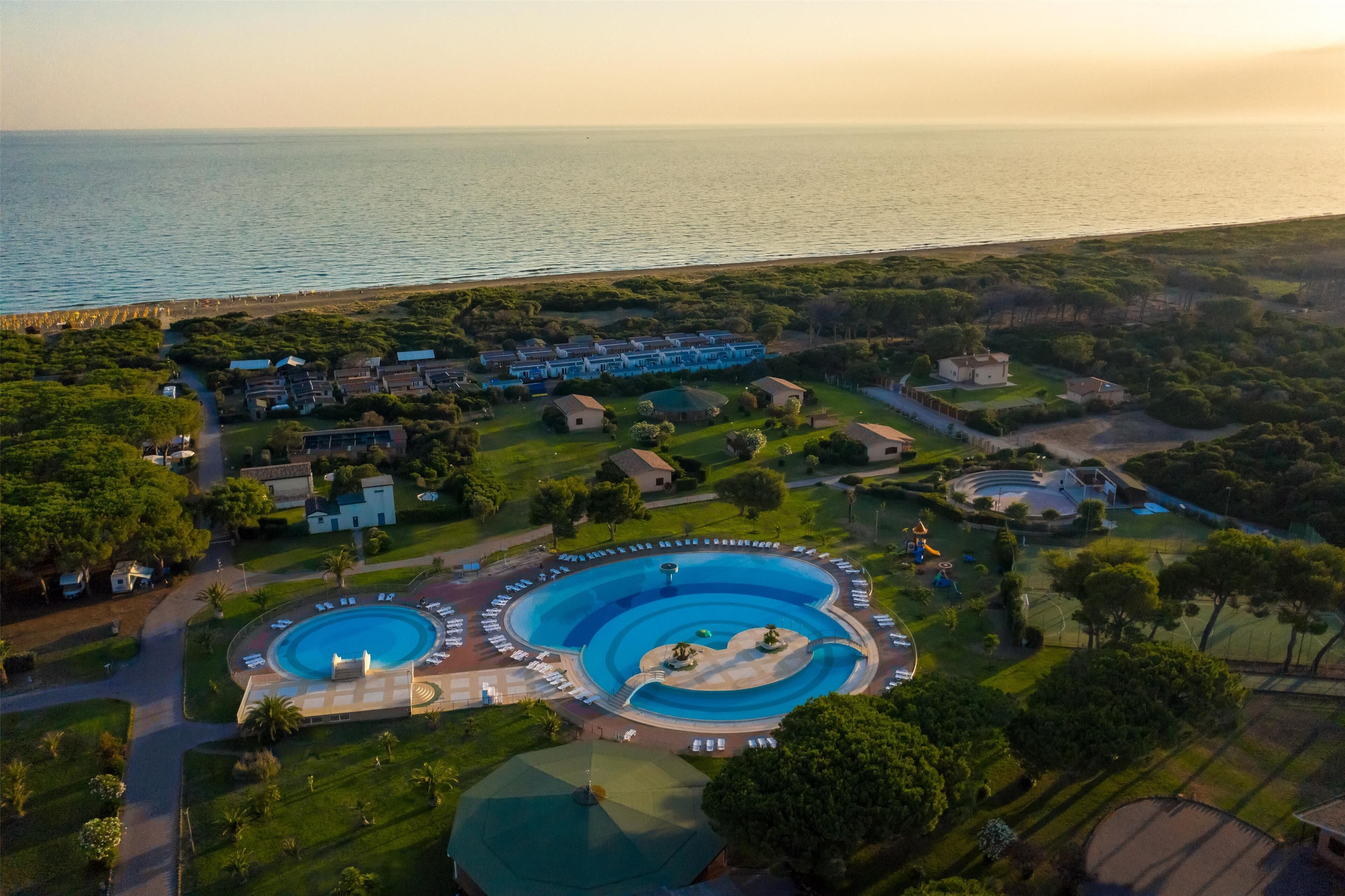Vista aérea de un resort con múltiples piscinas, una playa y un campo de golf.
