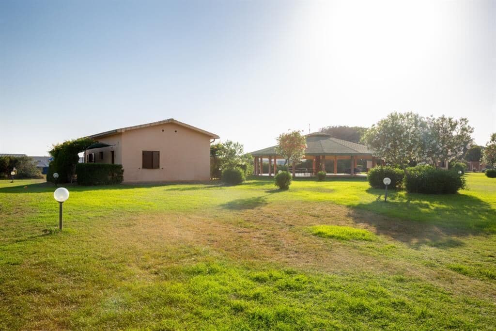 A residential property with a single-story house, a covered patio, and a well-maintained lawn.
