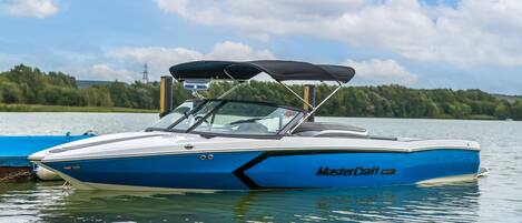 A blue and white boat with a canopy, docked on calm water.