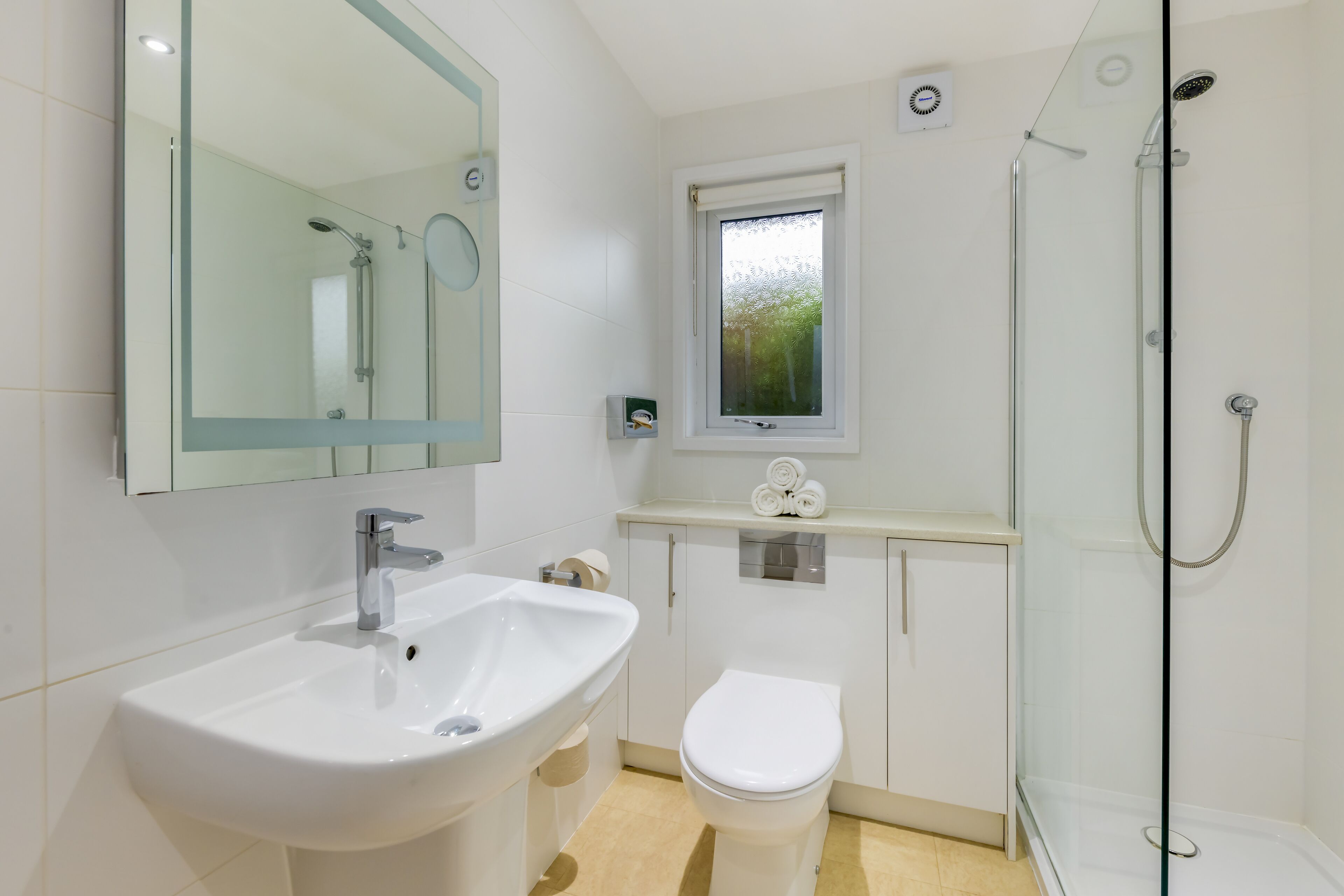 A modern bathroom with a glass shower enclosure, a white sink, and a toilet.