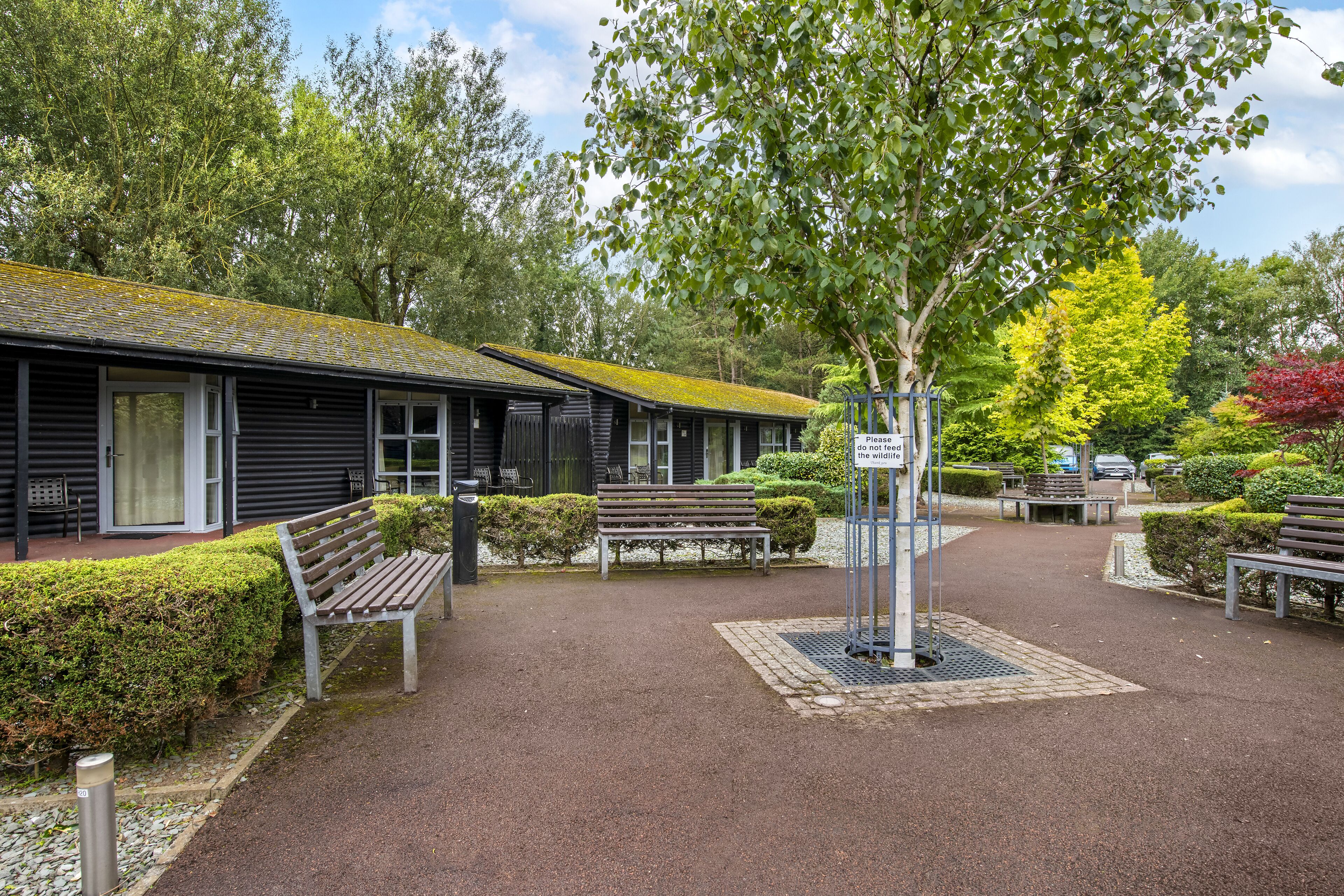 A building with a sloped roof, benches, and a sign.