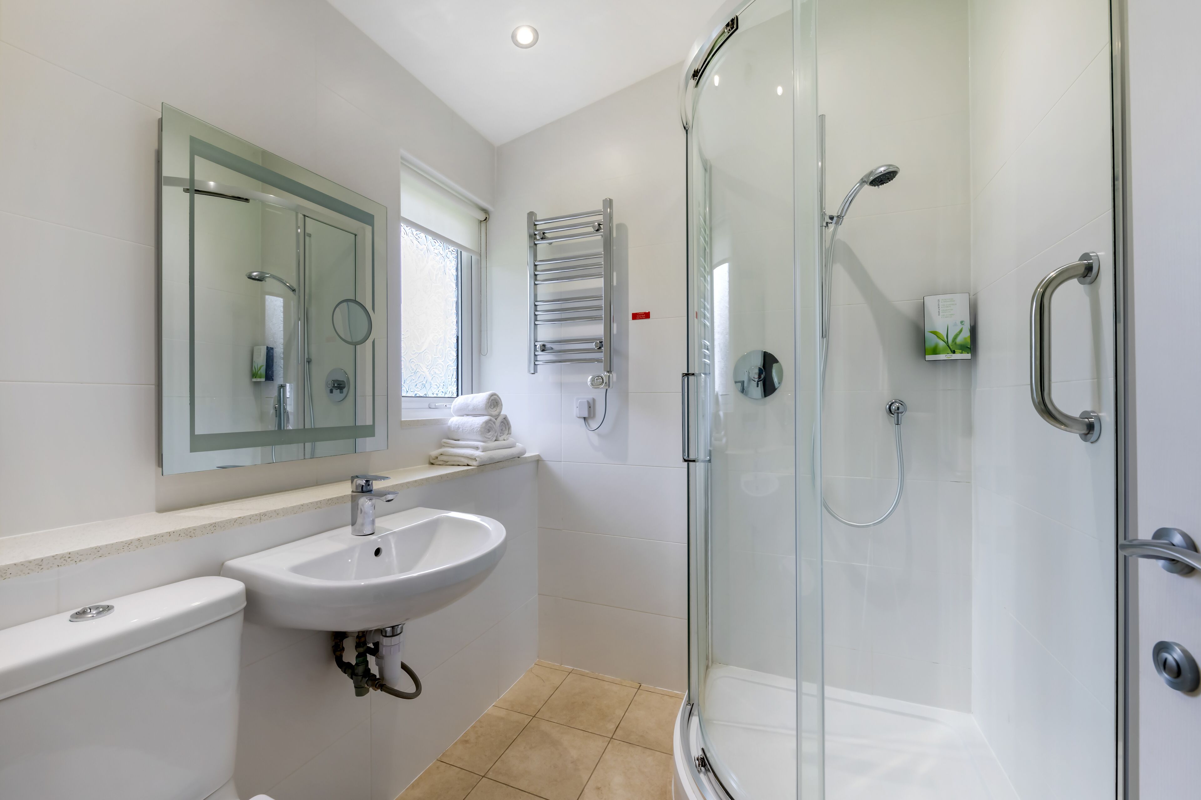 A modern bathroom with a glass-enclosed shower, a white sink, and a mirror above the sink.