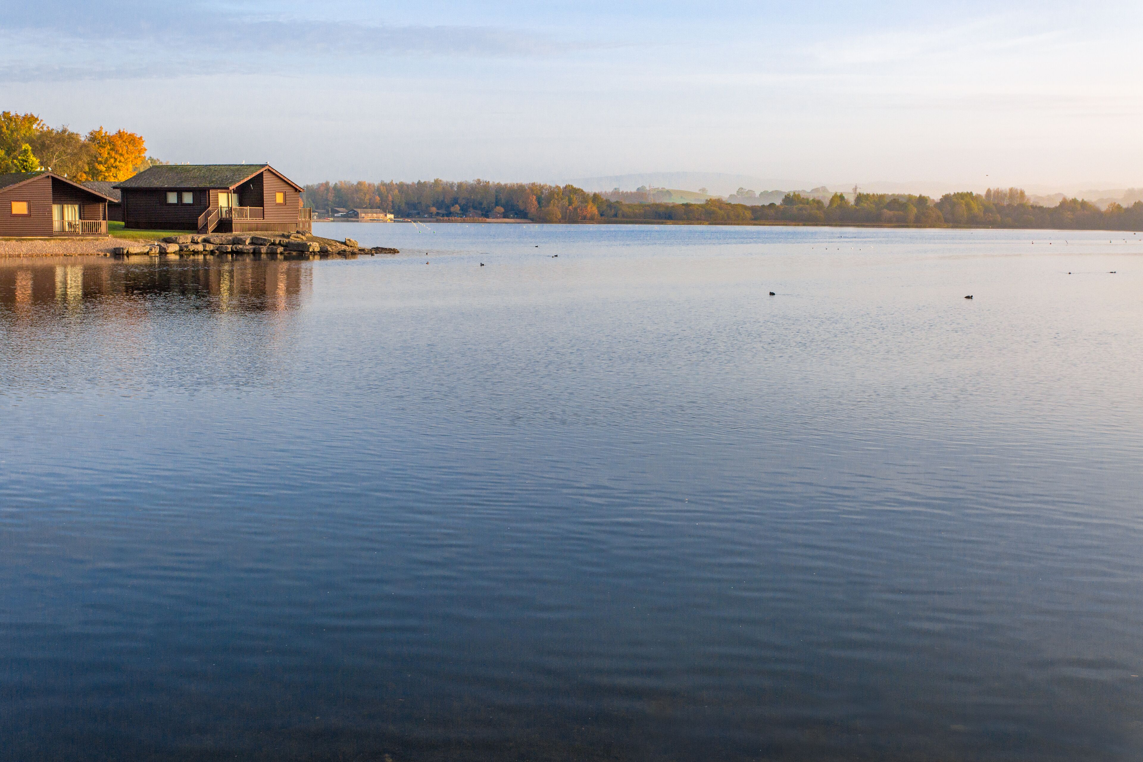 A calm lake with wooden cabins on stilts.