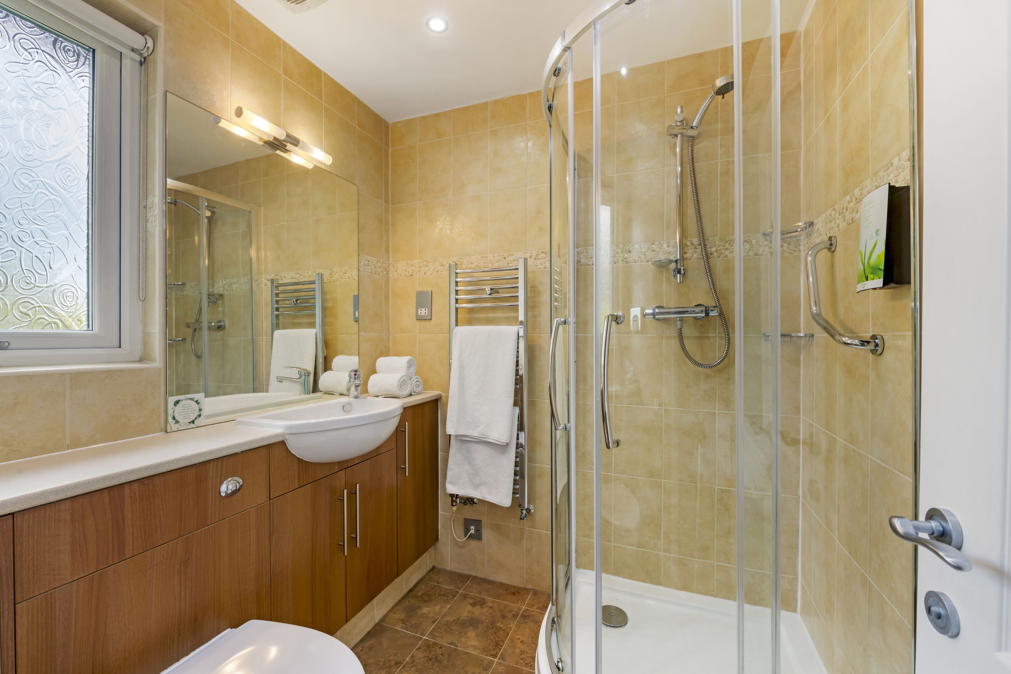 A modern bathroom with a glass-enclosed shower, a vanity with a sink, and a large mirror.