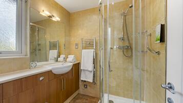 A modern bathroom with a glass-enclosed shower, a vanity with a sink, and a large mirror.
