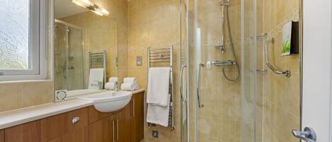 Une salle de bain moderne avec une douche à parois de verre, un meuble-lavabo et un grand miroir.