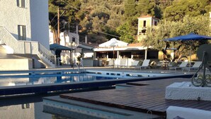 Zona de piscina amb gandules, una piscina petita i una zona de bar.
