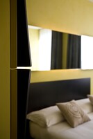 Quarto de hotel moderno com cama, almofadas e uma grande janela.