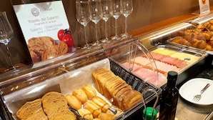 A breakfast buffet with various bread and pastries, a sign for 'friselle del Salento', and empty wine glasses. - Eos Hotel (Lecce)