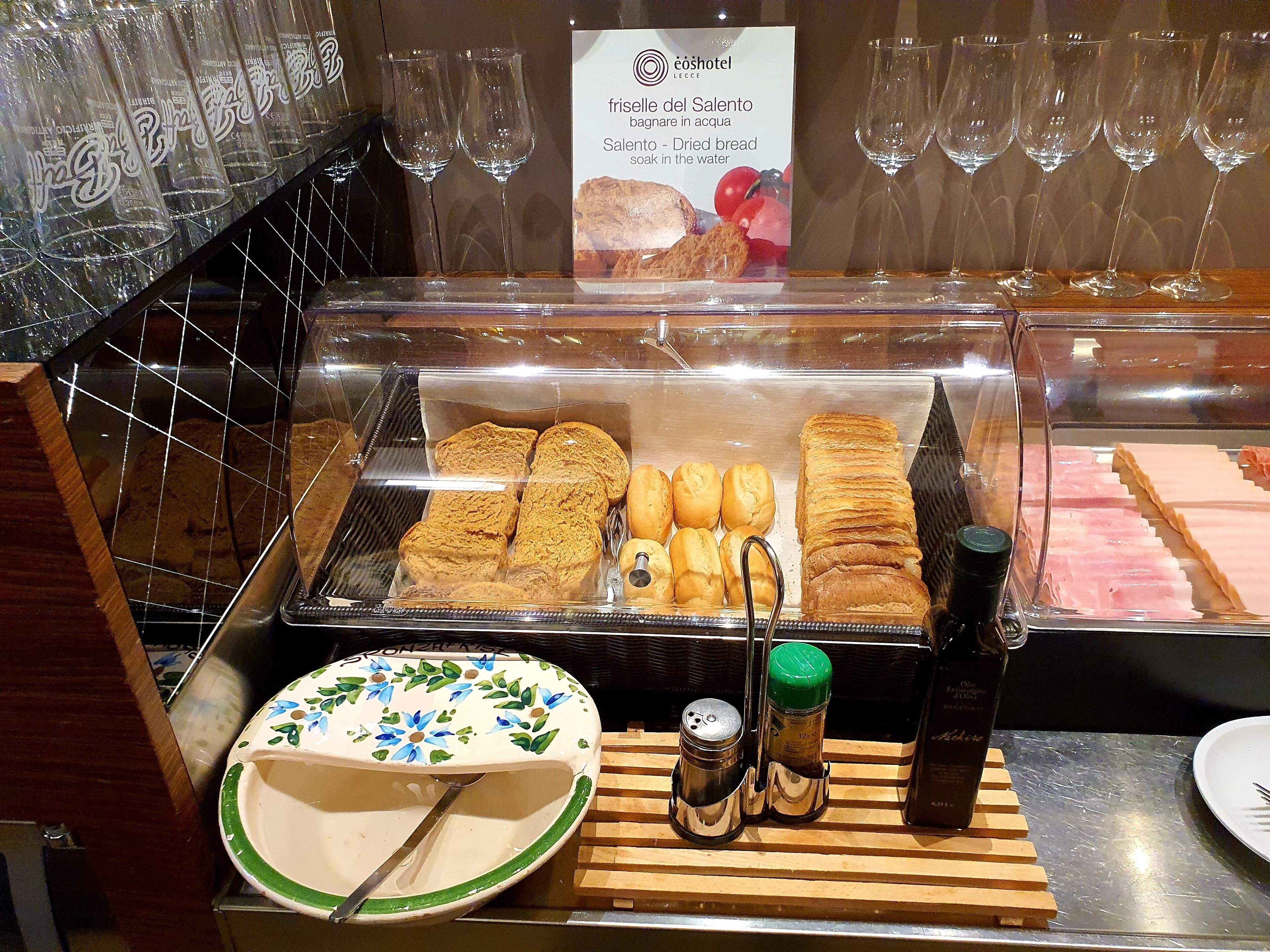 Ein Frühstücksbuffet mit verschiedenen Backwaren und Brot, einer Kaffeemaschine und Beilagen.