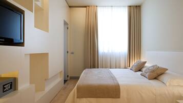 Une chambre d’hôtel moderne dotée d’un grand lit, d’un téléviseur à écran plat fixé au mur et d’un panneau de commande pour les équipements de la chambre.
