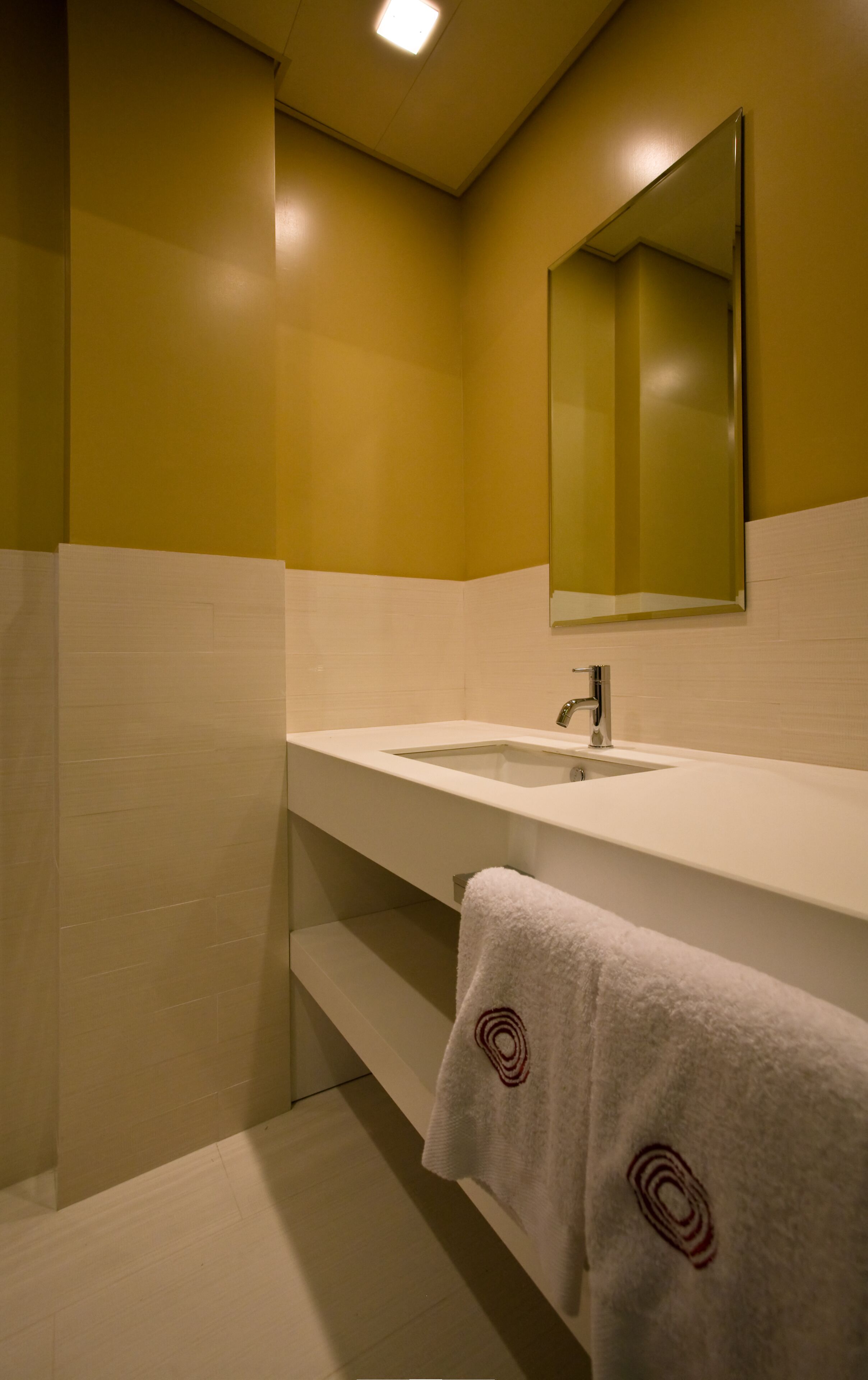A bathroom with a white sink, a mirror, and a towel with a circular design.