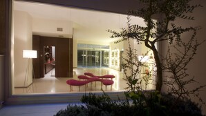 A modern interior with a glass wall reflecting a seating area and a hallway. - Eos Hotel (Lecce)
