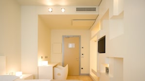 A hotel room with a bed, bedside tables, a TV mounted on the wall, and a door leading to another room. - Eos Hotel (Lecce)