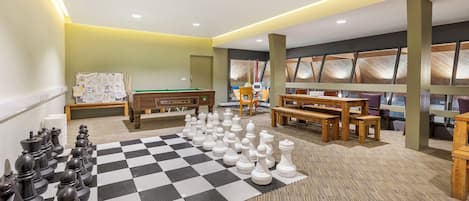 A spacious room with a large checkered carpet, a pool table, and multiple seating areas.