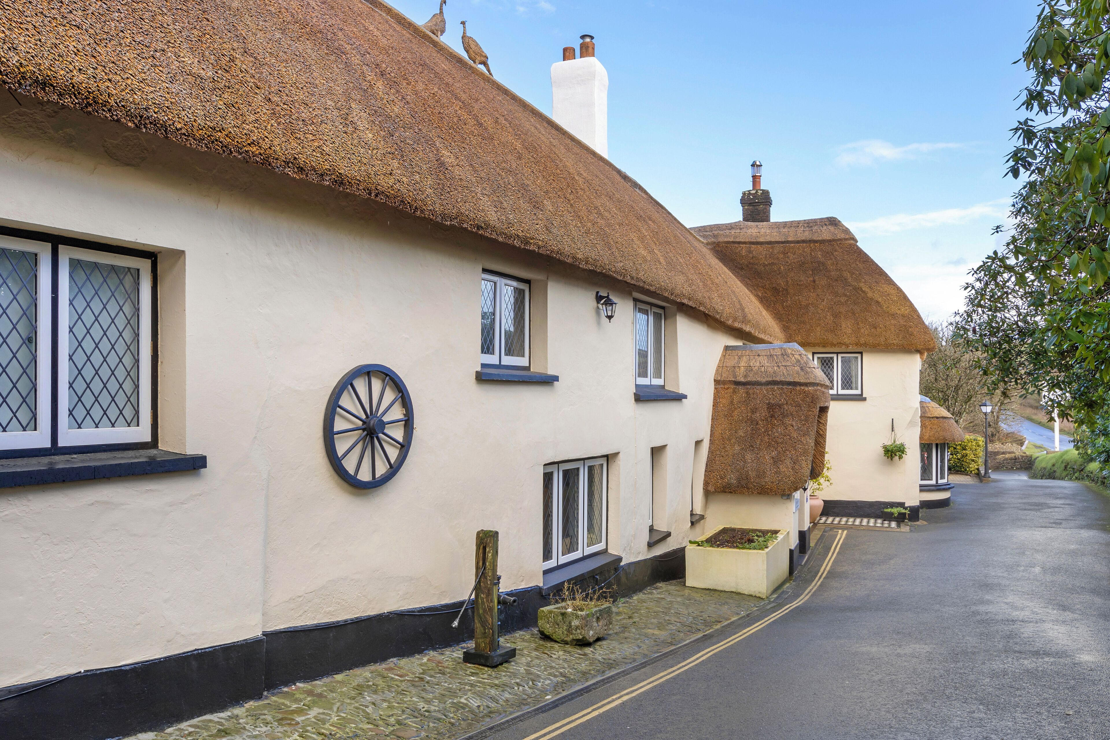 Une rangée de charmantes maisons traditionnelles aux toits de chaume, aux murs blancs et aux fenêtres à cadre noir.
