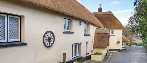 Une rangée de charmantes maisons traditionnelles aux toits de chaume, aux murs blancs et aux fenêtres à cadre noir.