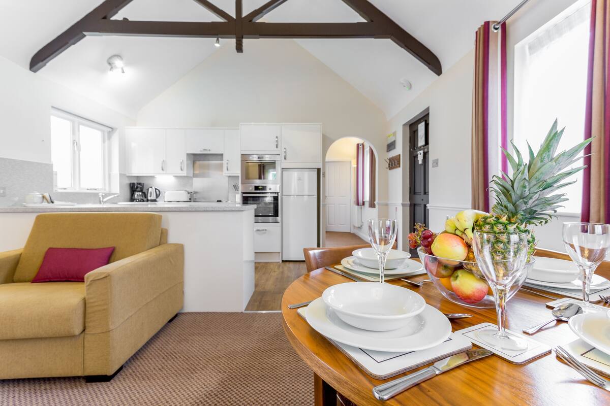 A modern kitchen with white cabinets and a dining area with a wooden table set for a meal.
