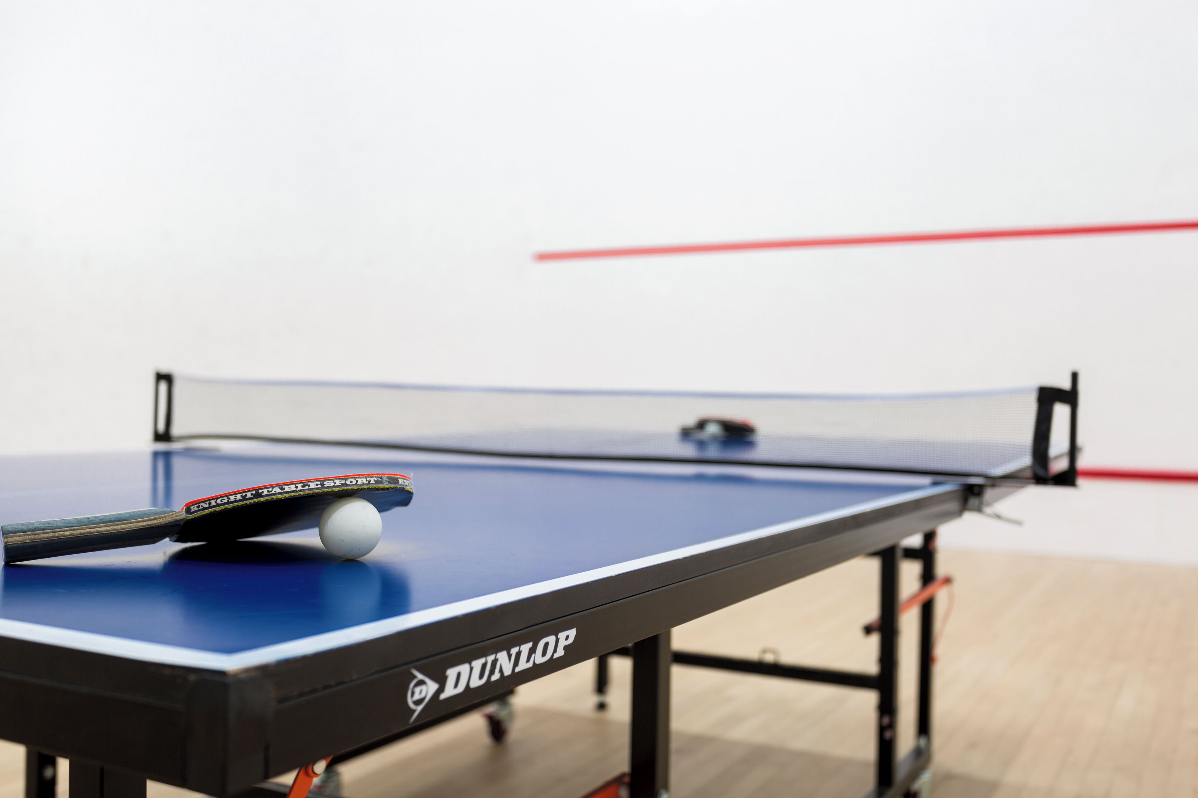 Een tafeltennistafel met een blauw speeloppervlak en een witte bal.