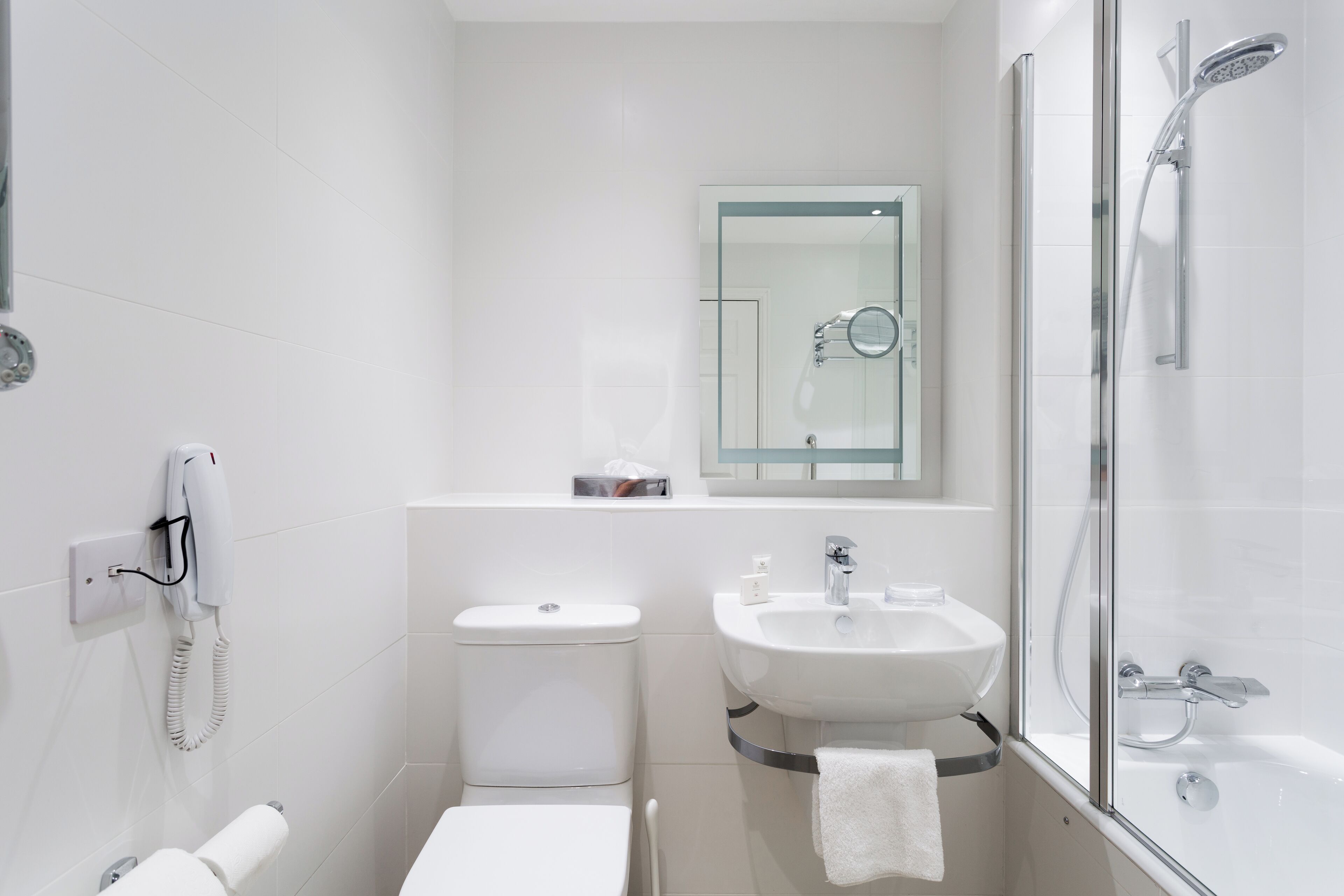 Un baño moderno con inodoro, lavabo y ducha con mampara de vidrio.
