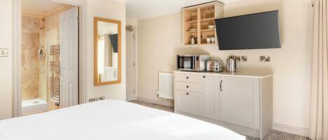 A hotel room with a large bed, a wardrobe, a television mounted on the wall, and a bathroom with a shower and toilet.