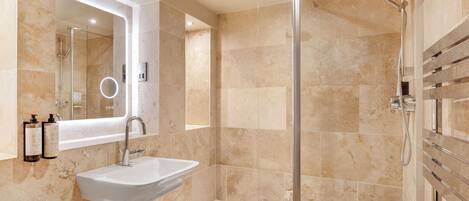 A modern bathroom with a white sink, a glass-enclosed shower, and a large mirror.