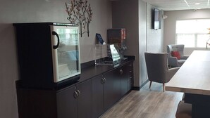 A modern kitchen with a refrigerator, a coffee machine, and a dining area with a table and chairs. - Microtel Inn & Suites by Wyndham Hoover/Birmingham (Birmingham)