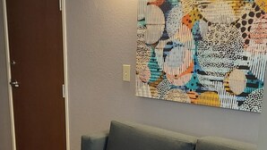 A modern room with a grey sofa, a wooden floor, and a colorful abstract painting on the wall. - Microtel Inn & Suites by Wyndham Hoover/Birmingham (Birmingham)
