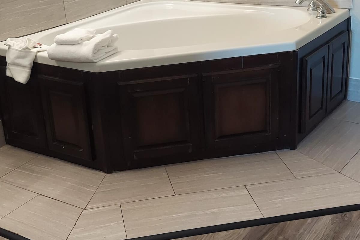 A modern bathroom with a freestanding bathtub, a large mirror, and a light fixture on the wall.