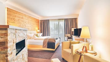 Ein Hotelzimmer mit Kamin aus Stein, einem Bett mit Kopfteil, einer Couch, einem Fernseher und einem Tisch mit Lampe und Flasche.