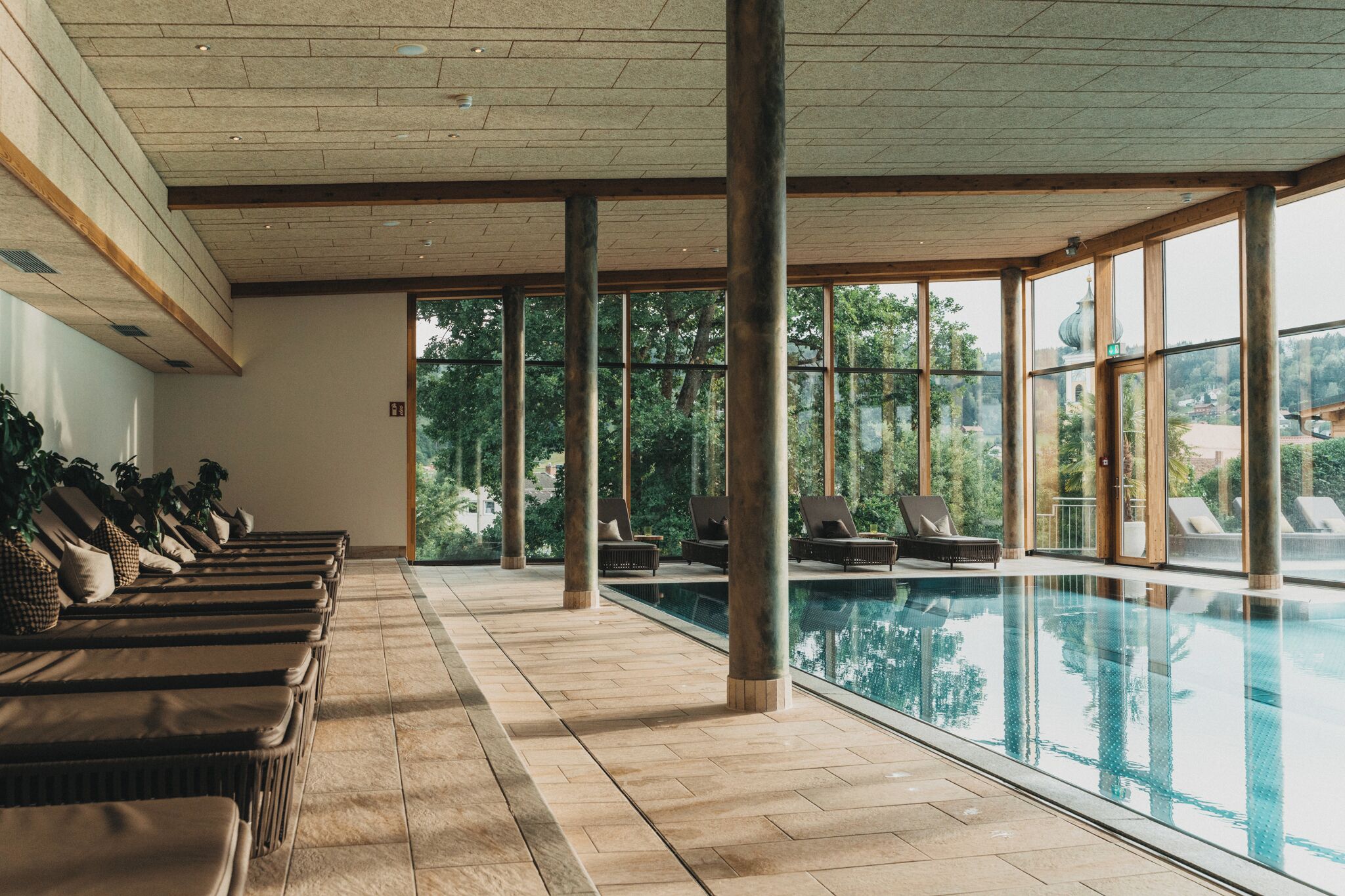 Un espace piscine doté de chaises longues et offrant une vue dégagée sur l’extérieur.