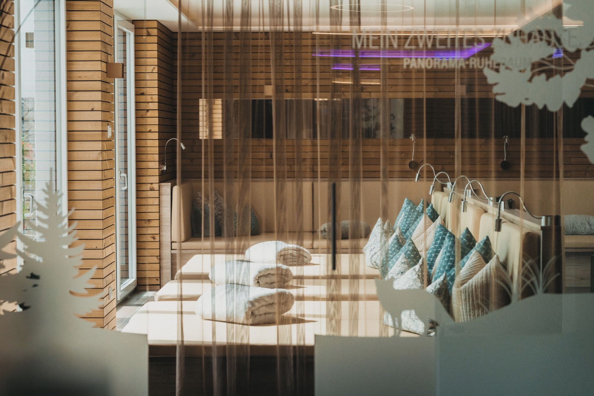 A hotel room with a wooden wall, a bed with multiple pillows, and a window with blinds.