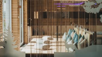 A hotel room with a wooden wall, a bed with multiple pillows, and a window with blinds.