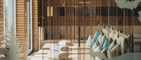 A hotel room with a wooden wall, a bed with multiple pillows, and a window with blinds.