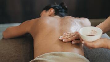 A person receiving a back massage with a bowl of cream.