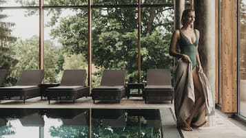 A poolside area with lounge chairs and a large window overlooking a forested area.