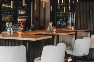 A bar area with wooden tables, bar stools, and a beer tap.