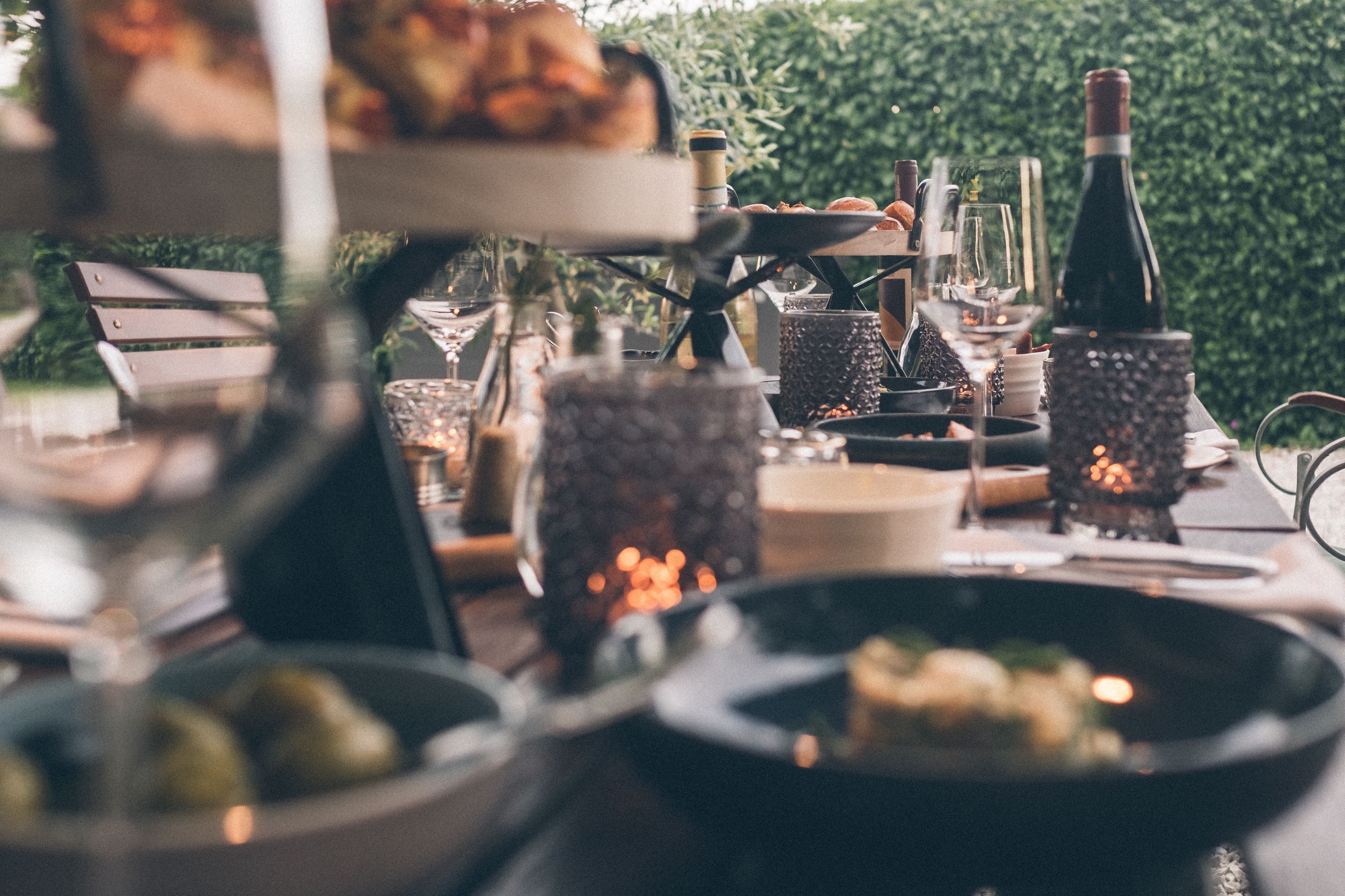 A dining table set with various dishes, glasses, and a bottle of wine, surrounded by decorative candles.