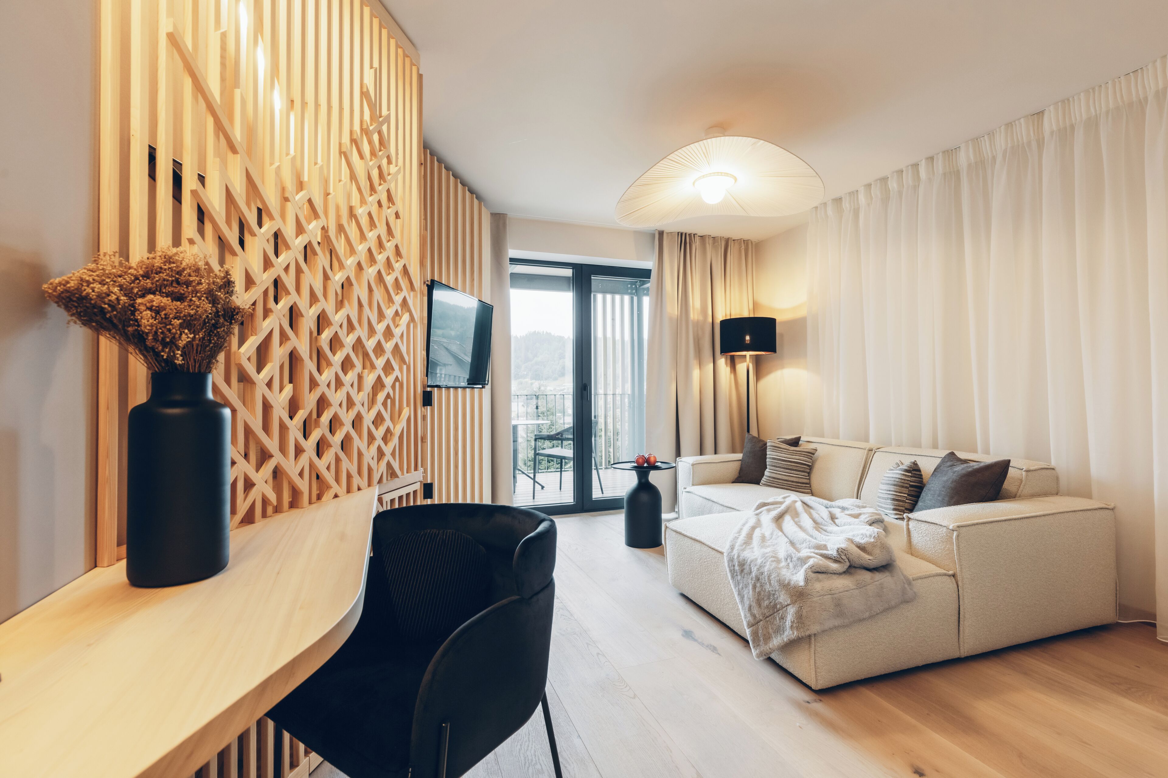 Una sala de estar moderna con un sofá, una mesa de centro, un televisor y un jarrón decorativo.