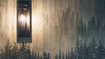 Pared con una lámpara de luz vertical y un diseño silueta de bosque.