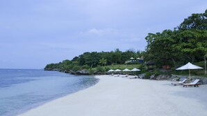 A beach with white sand, clear blue water, and several white umbrellas and lounge chairs. - Eskaya Beach Resort and Spa (Panglao)