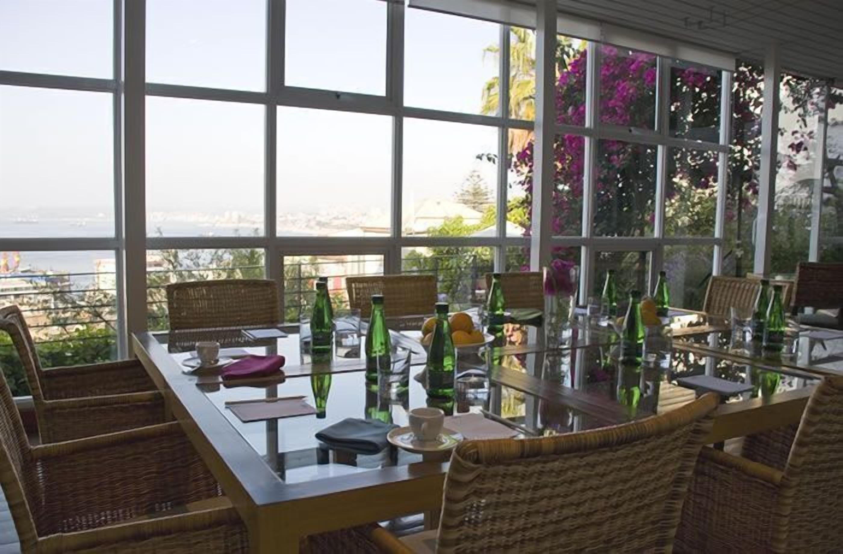 Un coin repas avec une table en verre et des chaises en osier, offrant une vue panoramique.